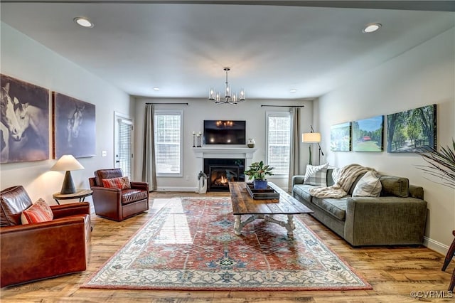 living room featuring a wealth of natural light, a notable chandelier, and light hardwood / wood-style flooring