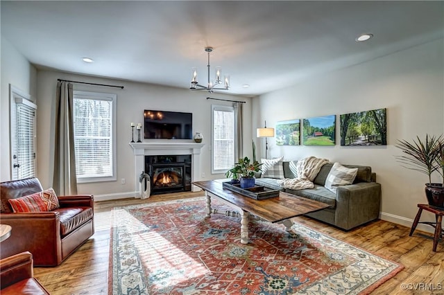 living room featuring light wood-type flooring, plenty of natural light, and a notable chandelier