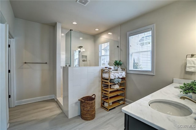 bathroom featuring hardwood / wood-style flooring, vanity, and a shower