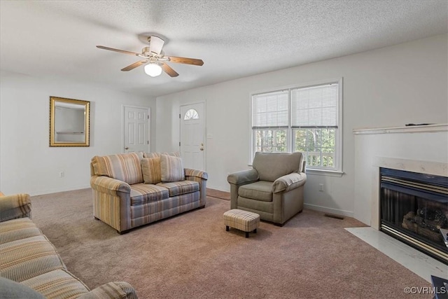 living room with a textured ceiling, ceiling fan, and light colored carpet