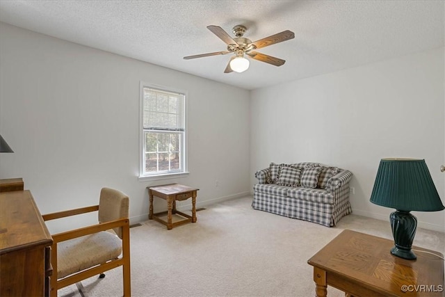 living area with a textured ceiling, ceiling fan, and light colored carpet