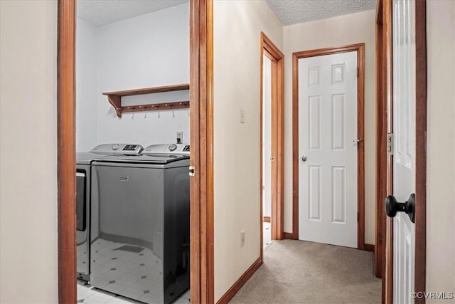 washroom with washing machine and dryer, light carpet, and a textured ceiling