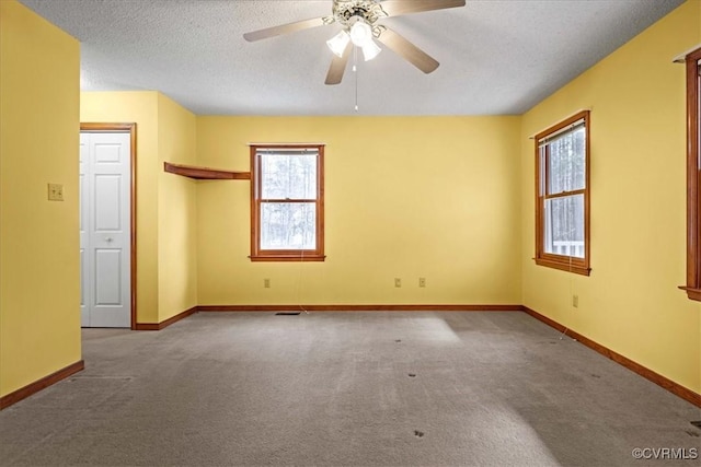 empty room with a textured ceiling, light colored carpet, and ceiling fan