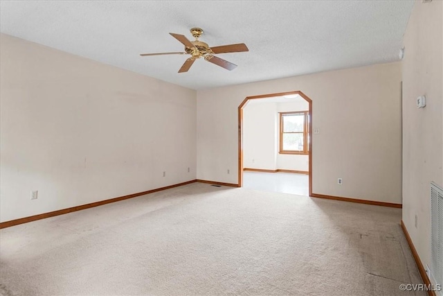 empty room with a textured ceiling, light colored carpet, and ceiling fan