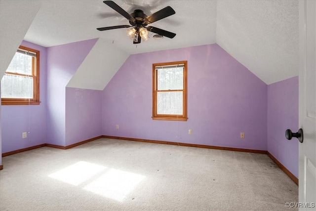 bonus room featuring ceiling fan, light carpet, a textured ceiling, and lofted ceiling