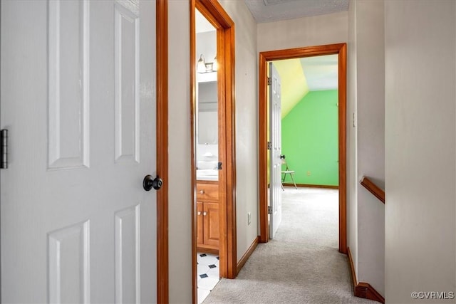 hallway featuring lofted ceiling and light colored carpet