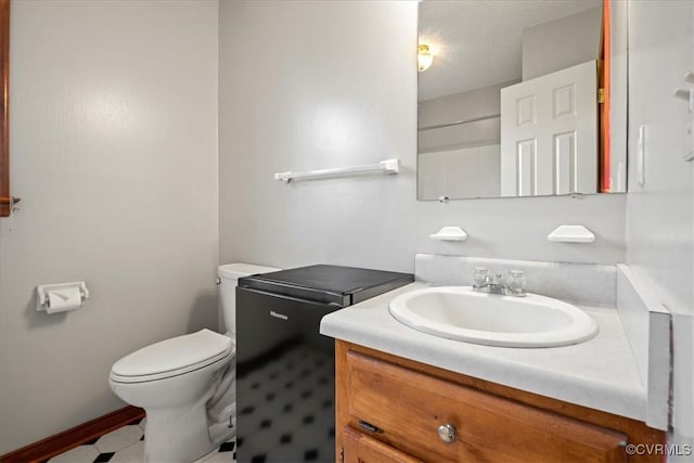 bathroom with vanity, toilet, and a textured ceiling