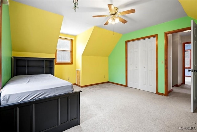 unfurnished bedroom featuring ceiling fan, a closet, light colored carpet, and lofted ceiling