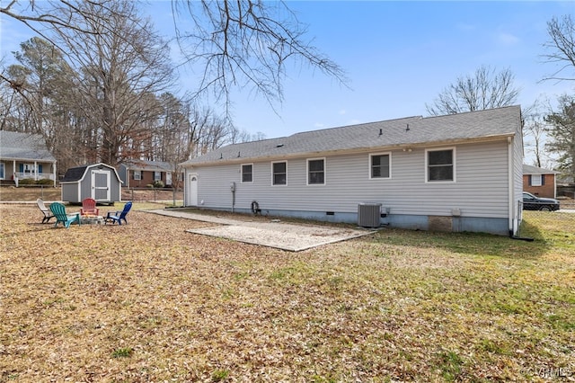 rear view of property featuring a patio, a lawn, a storage unit, and central AC