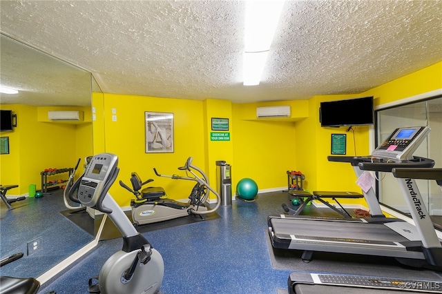 exercise room with a textured ceiling, baseboards, and a wall mounted AC