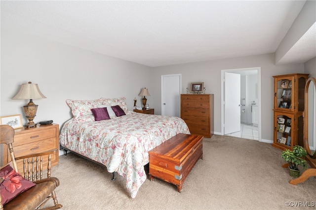 bedroom featuring light carpet, ensuite bathroom, and baseboards