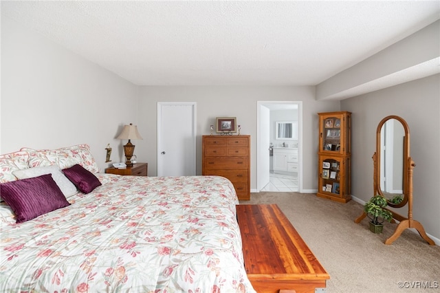 bedroom featuring ensuite bath, baseboards, a textured ceiling, and light colored carpet