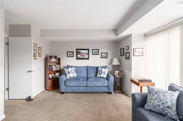 living area featuring light carpet, a textured ceiling, and baseboards