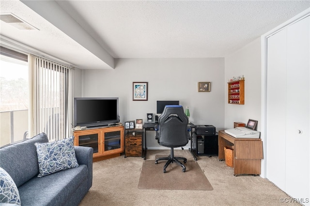 office area featuring visible vents, a textured ceiling, and light colored carpet