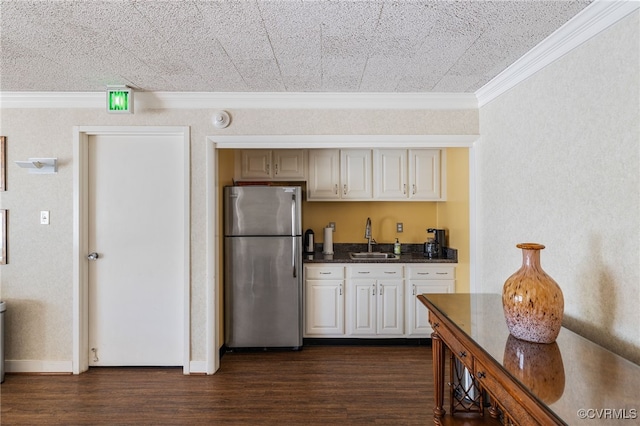 kitchen featuring a sink, freestanding refrigerator, dark wood-style floors, dark countertops, and crown molding