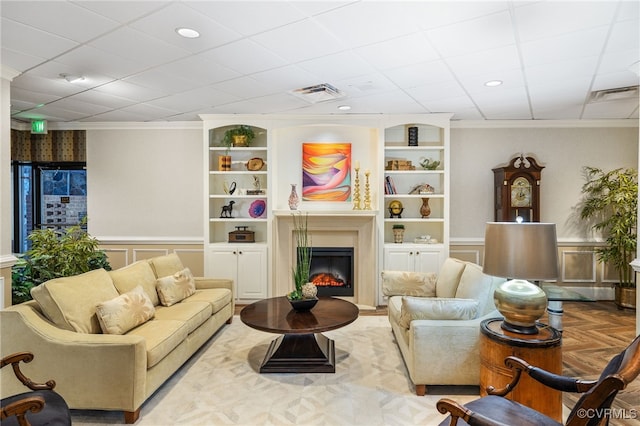 sitting room with wainscoting, a glass covered fireplace, visible vents, and built in features