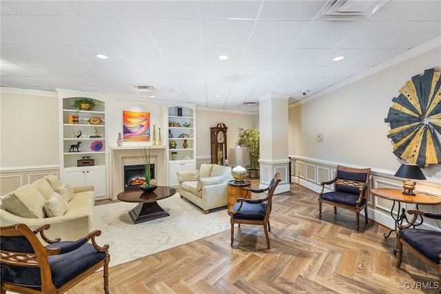 living area featuring visible vents, a fireplace, built in features, and ornamental molding