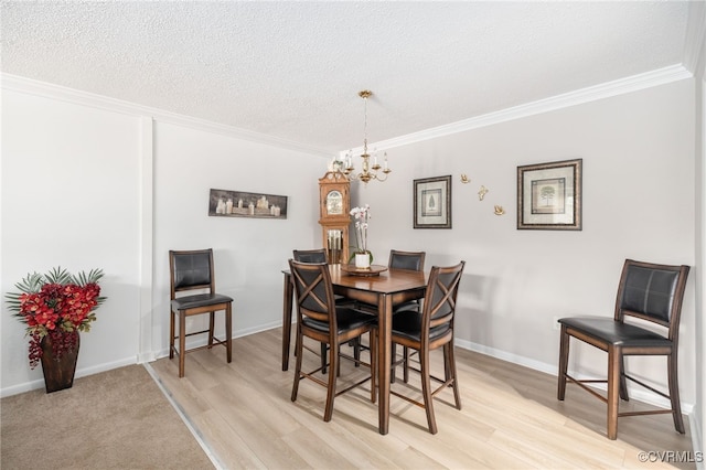 dining space with ornamental molding, a textured ceiling, and light wood finished floors