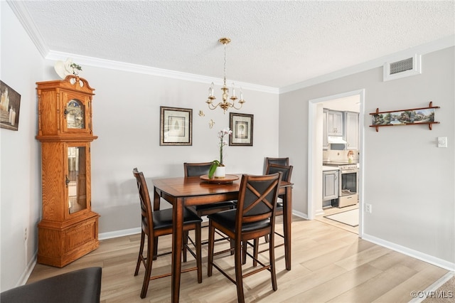 dining space with a textured ceiling, visible vents, and light wood-style floors