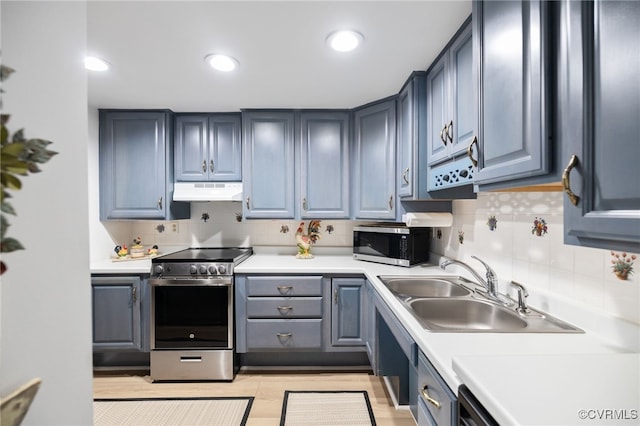 kitchen with stainless steel appliances, tasteful backsplash, light countertops, a sink, and under cabinet range hood