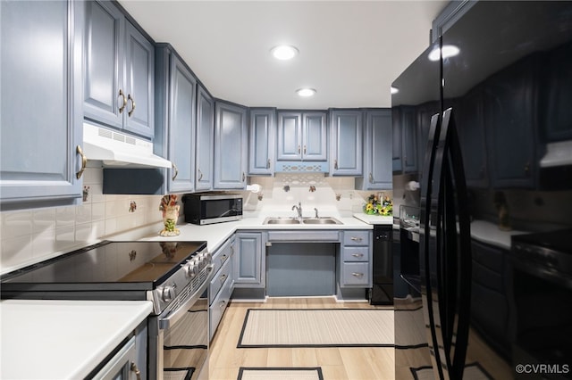 kitchen featuring stainless steel appliances, light countertops, light wood-style floors, a sink, and under cabinet range hood