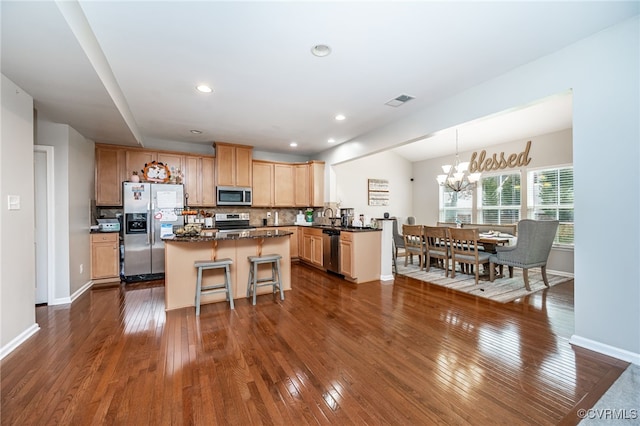 kitchen with dark countertops, visible vents, a kitchen island, stainless steel appliances, and a sink