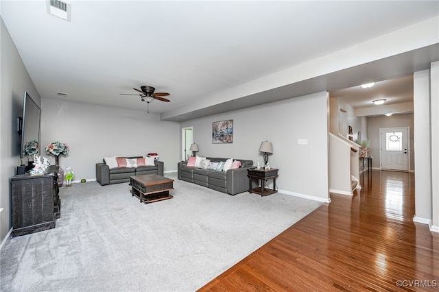 living room featuring a ceiling fan, wood finished floors, visible vents, baseboards, and carpet flooring