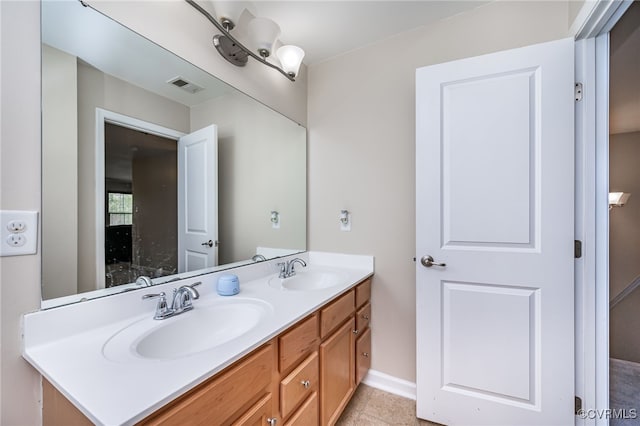 bathroom with double vanity, baseboards, visible vents, and a sink