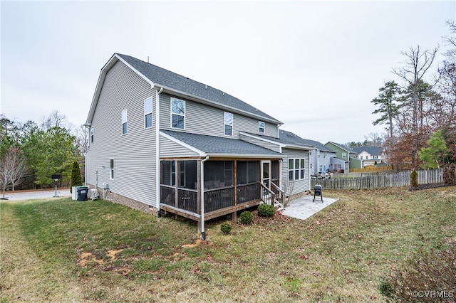 rear view of house with a lawn, a shingled roof, fence, a sunroom, and a patio area