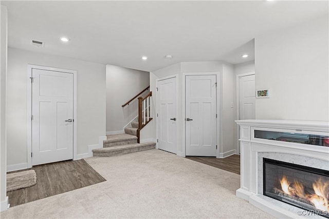 unfurnished living room with visible vents, recessed lighting, a high end fireplace, and stairs