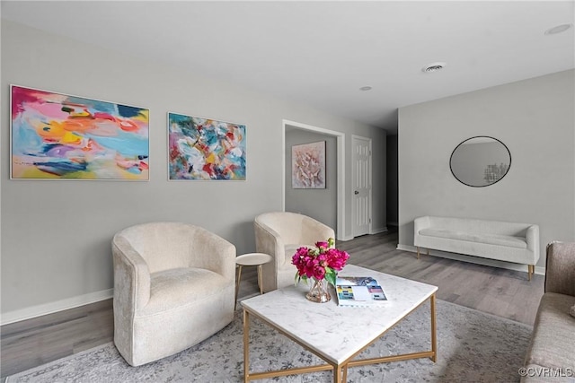 living area with visible vents, baseboards, and wood finished floors