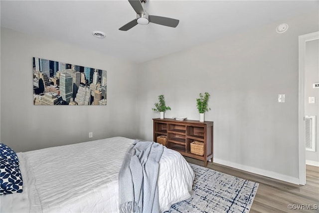 bedroom featuring a ceiling fan, baseboards, visible vents, and wood finished floors