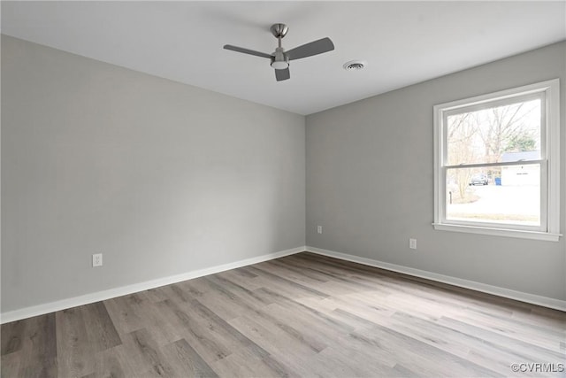 spare room featuring ceiling fan, wood finished floors, visible vents, and baseboards