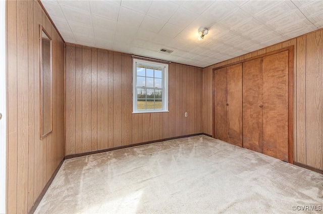 carpeted spare room featuring wood walls