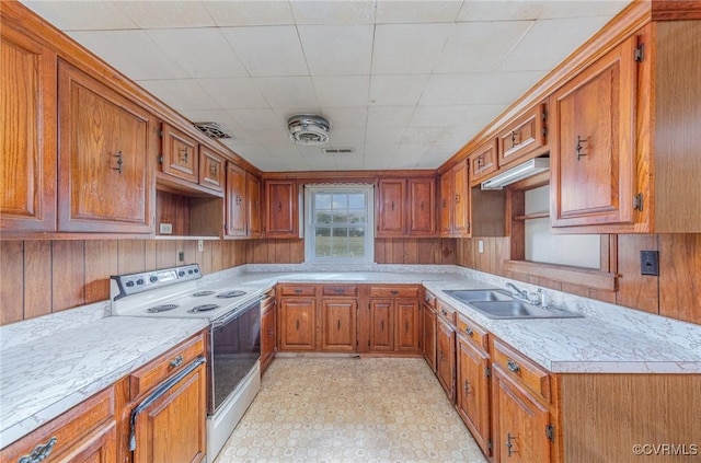 kitchen with sink, white range with electric stovetop, and wooden walls