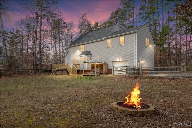 back house at dusk featuring a fire pit and a wooden deck