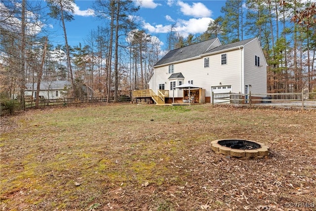 back of house featuring a yard, a wooden deck, and a fire pit