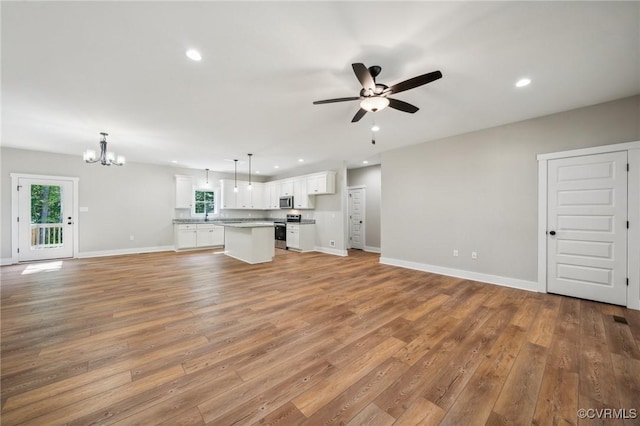 unfurnished living room featuring sink, light hardwood / wood-style floors, and ceiling fan with notable chandelier