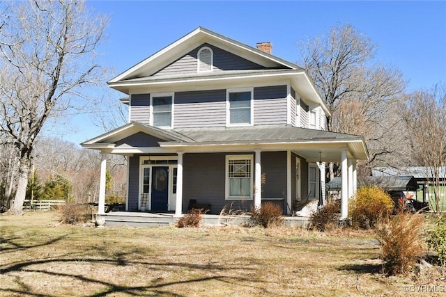 view of front of home with a front yard, covered porch, and a chimney