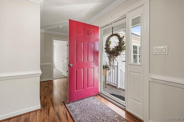 foyer with wood finished floors, baseboards, and ornamental molding