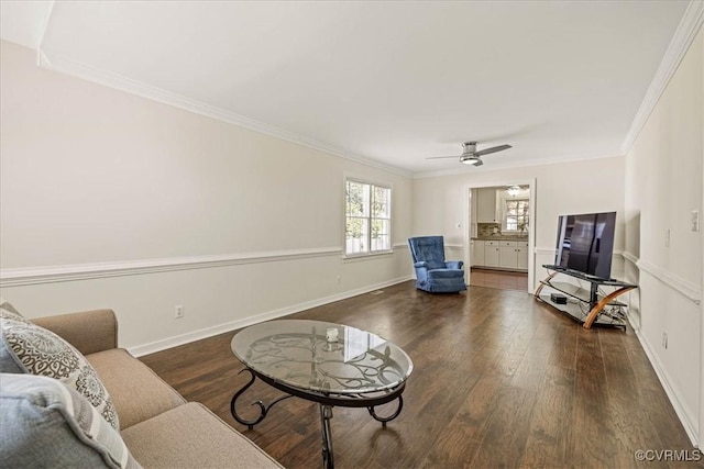 living area with ornamental molding, ceiling fan, baseboards, and wood finished floors