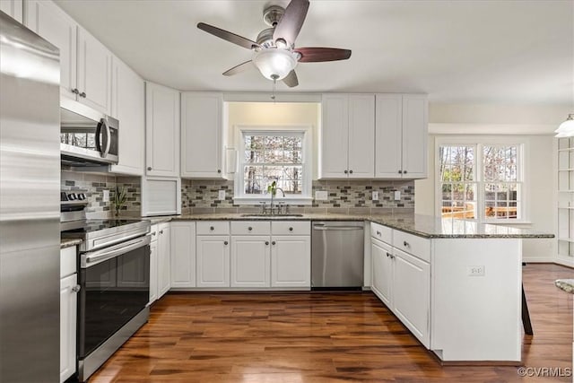 kitchen with white cabinets, appliances with stainless steel finishes, and a peninsula