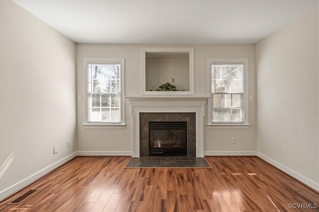 unfurnished living room featuring visible vents, baseboards, wood finished floors, and a fireplace