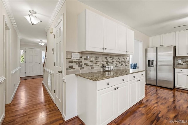 kitchen with dark wood-style flooring, ornamental molding, stainless steel refrigerator with ice dispenser, white cabinetry, and tasteful backsplash