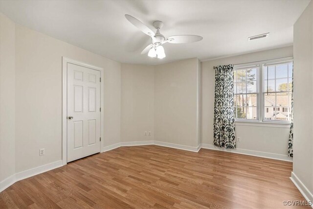 unfurnished room with a ceiling fan, wood finished floors, visible vents, and baseboards