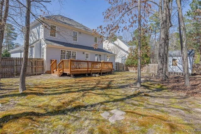 back of property with a deck, a fenced backyard, and a lawn