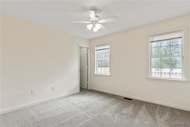 carpeted spare room featuring ceiling fan and plenty of natural light