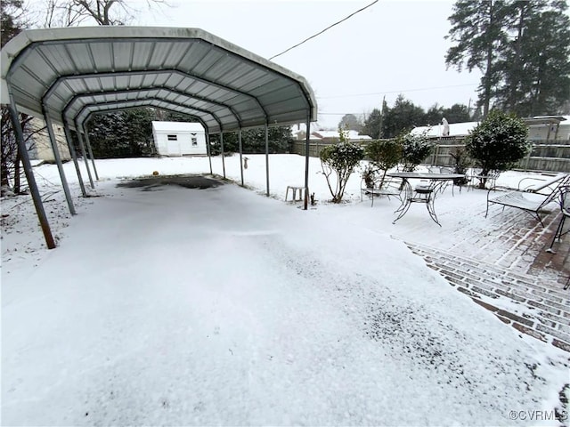 snow covered parking area with a carport