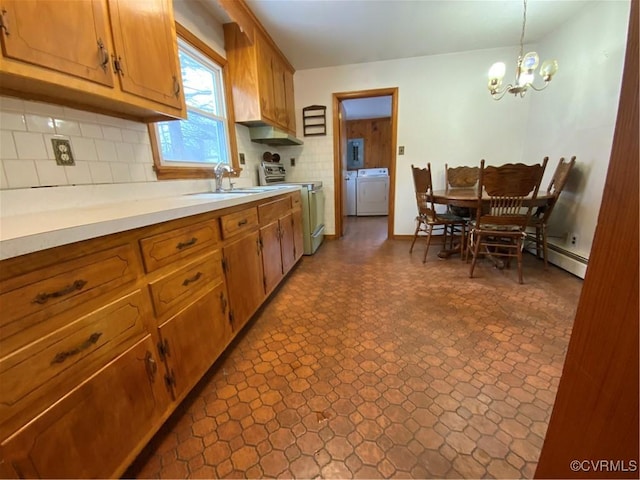 kitchen with sink, washer and clothes dryer, stainless steel electric range, hanging light fixtures, and tasteful backsplash