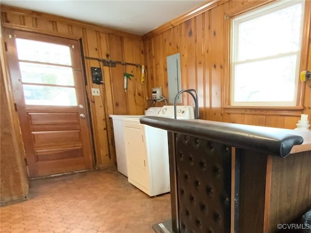 laundry area with electric panel, washer and clothes dryer, and wood walls